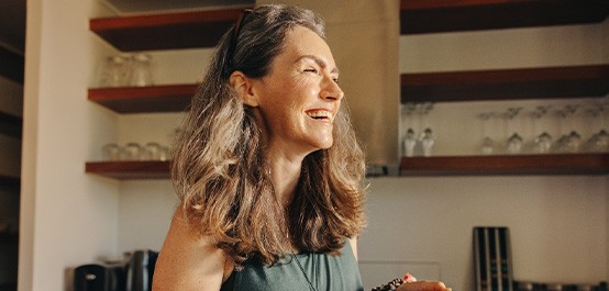 Smiling woman in kitchen holding wooden bowl of salad