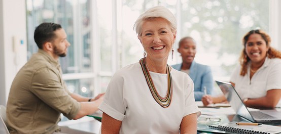 Woman in white blouse smiling with coworkers at a table