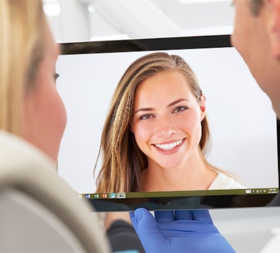 Patient and dentist looking at virtual smile design on computer screen