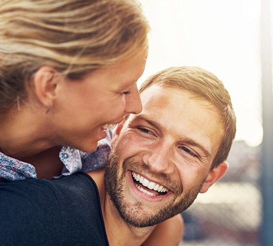 Man and woman smiling after dental implant tooth replacement