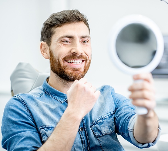 Man looking at smile after dental implant tooth replacement