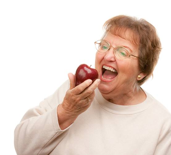 Older woman with dentures holding an apple
