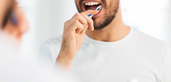 Nose-to-chest view of man brushing teeth