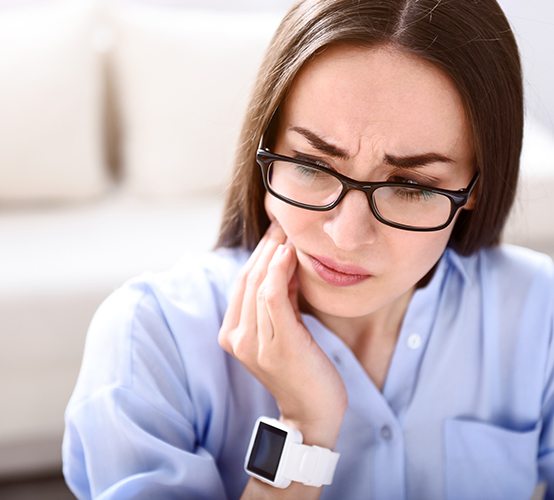 Woman in need of T M J therapy holding jaw in pain