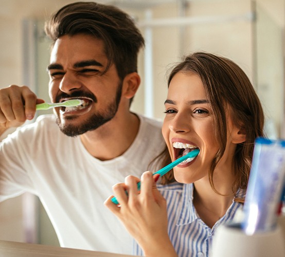 Man and woman brushing teeth to prevent dental emergencies