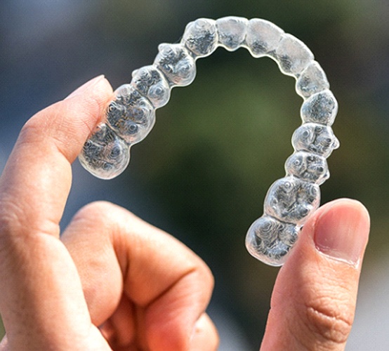 person holding Invisalign aligner