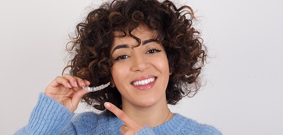 patient smiling while holding Invisalign in Owasso  