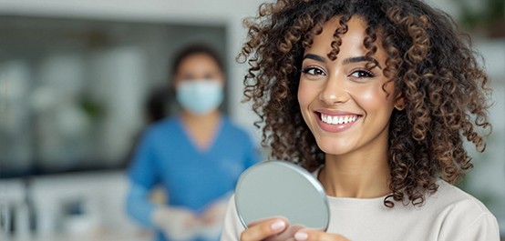 Woman smiling while holding small mirror