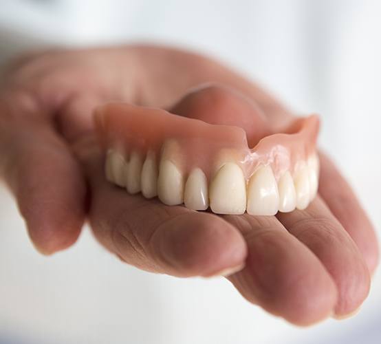 Hand holding a full denture