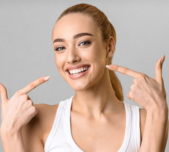 young woman smiling and pointing to veneers