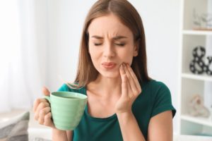 Woman who is experiencing dental pain with hand on cheek