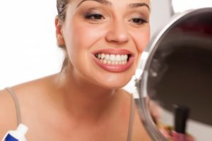 woman looking at teeth in mirror 