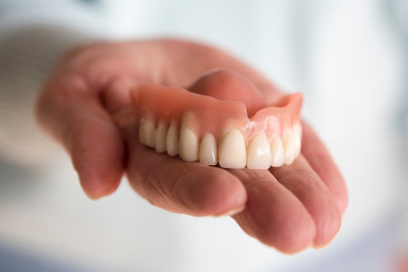 A closeup of a hand holding a full denture
