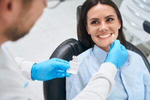 Dentist testing out different veneer shades on smiling patient.